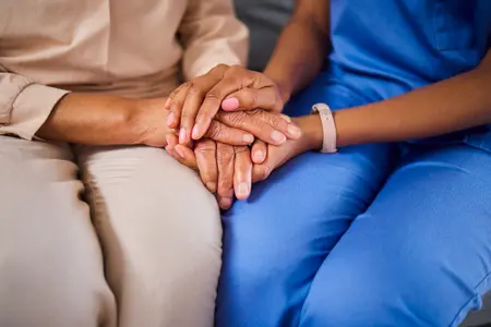 Profissional de saúde negra segura a mão de paciente negra